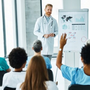 Doctor lecturing in front of students raising hand